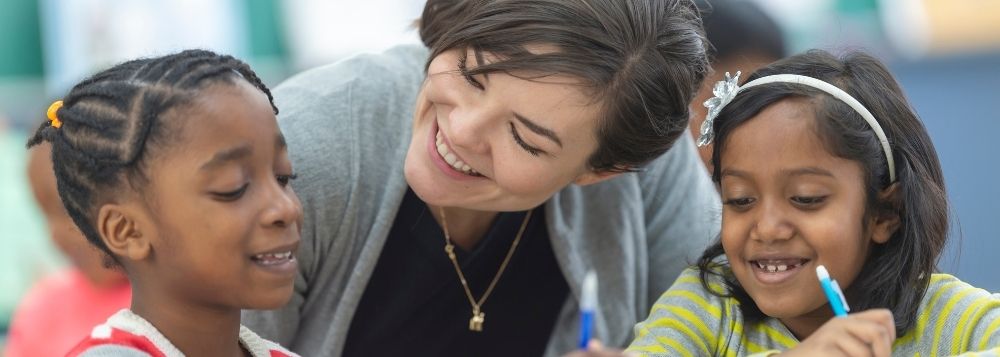 Teacher smiling with two students